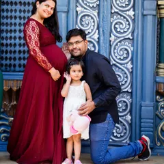 A classic family pose with a playful twist. The father leans in to "listen" to the baby bump, creating a fun and memorable photo with their daughter.