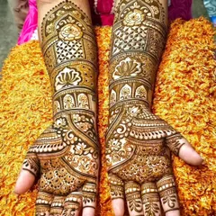 A classic and dense bridal design covering the full forearm. This style features traditional motifs like roses and lotuses set within architectural frames, with detailed work on the fingers.
