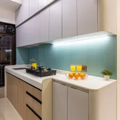 A complete kitchen transformation designed for efficiency and style. We used a refreshing palette of pastel blue fluted tiles, light wood, and grey laminates, along with clever storage, to create a bright, airy, and highly functional culinary space.