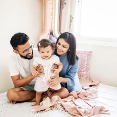 A happy family moment on the bed, celebrating their daughter's first birthday. These candid, at-home sessions are all about capturing genuine smiles and interactions.
