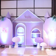 A custom-built purple fairy castle serves as the main photo backdrop. The design includes soft lighting and adorable mushroom props to create a complete fantasy world for the birthday girl.