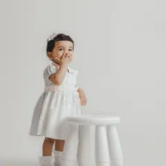 A shy, sweet moment from a toddler session. We use simple props like this white stool to create clean, timeless portraits that highlight your child's expressions.