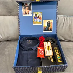 A sophisticated Rakhi gift hamper for a brother. This set includes a formal shirt, a personalized wallet and Fogg perfume, a rakhi, and chocolates, with custom photos displayed inside the lid of the box.