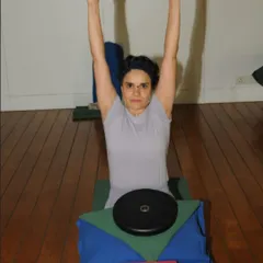 Here, a student uses a rod and weights to learn the correct action of the arms and shoulders. These props provide feedback, teaching the body to engage the right muscles and create stability and length, which is essential for healing.
