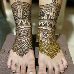 This is part of a step-by-step series showing a bridal foot design in progress. Here you can see the henna paste is still fresh on one foot, while the other is complete.