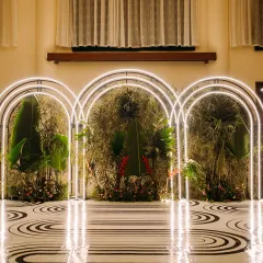 A modern and dramatic Sangeet stage featuring neon arches and tropical foliage, set against a custom-designed floor. This setup is perfect for a high-energy celebration.