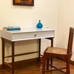 A simple and elegant study corner. This custom-designed desk features a clean white top and a dark wood frame, paired with a classic cane chair for a timeless look.