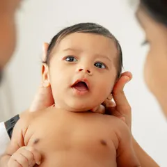 A close-up of a newborn's curious face, held gently by his parents. Those wide, wondering eyes are a beautiful thing to capture.