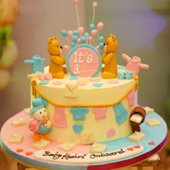 "It's a..." This gender reveal cake is full of suspense and sweetness! Decorated with teddy bears and a clothesline of baby outfits in pink and blue, it's a fun centerpiece for the big reveal.