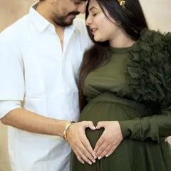 A close-up shot focusing on their hands creating a heart on the baby bump. It's a simple, sweet gesture that symbolizes all the love waiting for their little one. A classic pose for a maternity couple photoshoot.