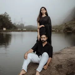 A stylish couple portrait by the lake in Vagamon. The misty background and coordinated black outfits create a dramatic and modern look for this pre-wedding photography session.