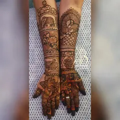 This design is filled with auspicious symbols. It features a Ganesha on the palm, along with elephants, lotuses, and other traditional motifs covering the full arm.