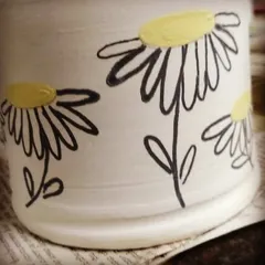 A peek at a piece being decorated behind the studio doors. This hand-painted daisy mug shows how you can add a personal touch to your pottery.