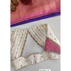 A beautiful example of a contrast design. This off white blouse features delicate pink floral embroidery and striped details. The unique back cutout and the contrasting pink patterned fabric on the sleeve cuff add a modern and playful element to a classic design.