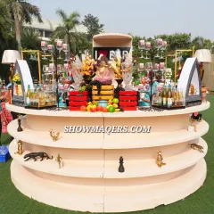 A custom-designed, multi-tiered bar for a Banaras-themed event. The setup is elaborately decorated with fresh fruit, flowers, and unique figurines, serving as a stunning centerpiece.