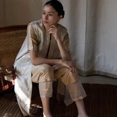 A pensive moment captured in natural light. This image highlights the soft drape of the fabric and the intricate details on the trousers, showing how versatile ethnic wear can be for everyday elegance.