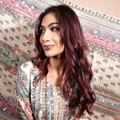 The ruby-toned hair styled in loose waves, perfectly complementing the client's traditional attire. This shows how a modern hair colour can beautifully pair with ethnic wear.
