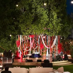 The amphitheater stage set for a Sangeet night, with a vibrant red and white ribbon backdrop, ready for music and dance performances.