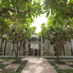 The beautiful glasshouse-style entrance to a modern wedding venue, framed by lush green trees.