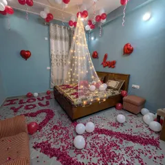 I transform ordinary bedrooms into romantic retreats. This setup features a sheer bed canopy with fairy lights, a floor scattered with rose petals, and balloon arrangements to create a cozy and intimate atmosphere.