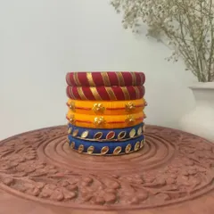 This stack of thread bangles in red, yellow, and blue is a classic festive combination. The set includes different designs, from gota patti work to mirror embellishments.