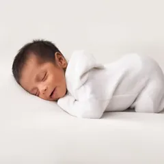 A pure and simple portrait on a clean white background. This pose, with the baby in a simple white outfit, focuses entirely on their perfect newborn form.