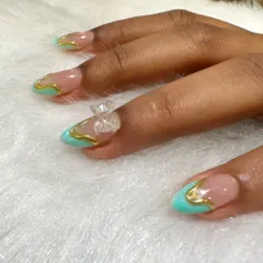 A close-up of a delicate and elegant 3D design. This look features a turquoise and gold outline design with a clear, sculpted 3D bow on the accent nail.