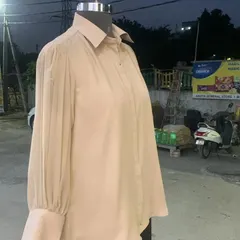 Another view of the custom-stitched beige shirt, showing the detail of the pleated sleeves and the clean, classic collar.