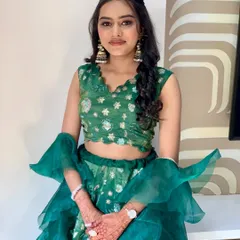 A full view of bridesmaid Bhakti's look. The green lehenga with ruffle details is fun and festive, and her makeup is fresh and glowing.
