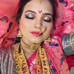 A close-up of the makeup for a Maharashtrian bride. The focus is on the eyes with golden eyeshadow and a sharp liner, paired with a pink lip and the essential `chandrakor` bindi.