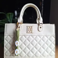 Here is our daisy keychain in a lovely olive green, adding a touch of nature-inspired charm to a classic white handbag. It's a simple way to refresh your accessories for the season.