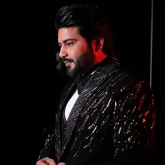 A profile shot of our client in an exclusive handcrafted tuxedo. The dramatic lighting highlights the texture and shimmer of the sequin and beadwork on the lapels and shoulders.