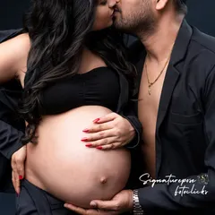 An intimate and modern couple's portrait, sharing a kiss while cradling the bump. A truly powerful image of partnership.