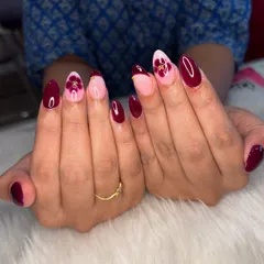Blooming with perfection. This set features a deep maroon polish with accent nails showing a delicate blooming flower effect and a modern French tip, all tied together with tiny gold details.