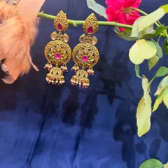 A pair of beautiful antique gold finish earrings with pink stones and jhumki details. These are perfect for adding a touch of tradition to any outfit.