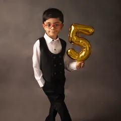 Five and fabulous! This young man is celebrating his fifth birthday in style, holding a golden '5' balloon against a classic charcoal backdrop.