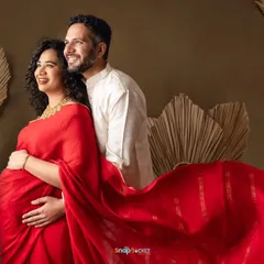 A beautiful couple's portrait celebrating their heritage. Her flowing red saree and his traditional white kurta create a stunning and coordinated look for their maternity session.