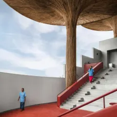 The grand staircase at the TAPMI Centre, finished in a vibrant red oxide, guides movement through the open, multi-level space. The design encourages a non-linear journey, connecting different zones and activities.