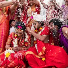 A vibrant and joyous moment as the couple is showered with rice and blessings by their families during a traditional South Indian wedding ceremony.