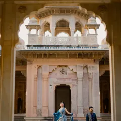 A creative shot using the palace arches to frame the bride as she looks up with a smile. This composition highlights the bride's happiness and the grandeur of the location, creating a dynamic and engaging portrait.