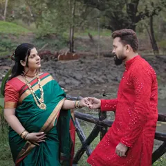 A classic couple's portrait from a traditional maternity session. The contrast of her green saree and his vibrant red kurta makes for a visually striking image, celebrating their journey together.