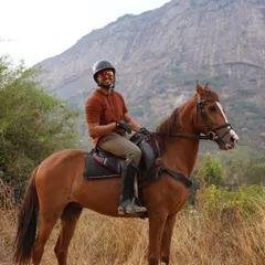 A happy rider on his handsome brown horse, pausing to enjoy the view during a safari ride through the hills.