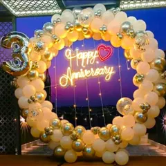 A beautiful balloon ring decoration for a 3rd wedding anniversary. The white and gold balloons are complemented by a 'Happy Anniversary' neon sign.