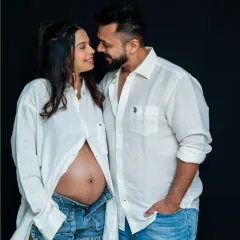 A beautiful, relaxed studio portrait of a couple. Their matching white shirts and the mom-to-be's bare bump create a natural and intimate feel.
