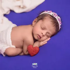 Simple, classic, and all about the baby. This side-lying pose on a vibrant purple backdrop highlights the baby's delicate features and peaceful sleep.