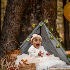 A joyful shot of the birthday girl clapping her hands inside her little tent. Her bright expression and the festive setting perfectly capture the spirit of a first birthday celebration.
