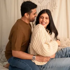 Capturing pure, unscripted joy. This candid photo shows a couple sharing a laugh during their cozy, casual maternity photoshoot in the studio.