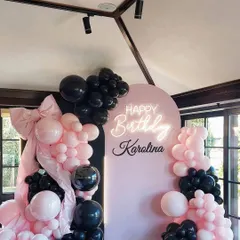 A stylish pink and black theme for a house party, featuring a custom arched backdrop with a neon sign and a beautiful balloon garland.