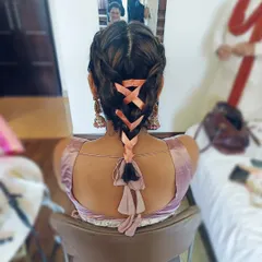 A modern take on a traditional braid, this style features a Dutch braid woven with a peach-colored ribbon. This is a creative and personalized look for a fun pre-wedding event.