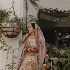 The stunning bride, Ashima, shares a joyful, candid smile. Her pastel lehenga and traditional jewelry are perfectly complemented by the natural, happy moment.